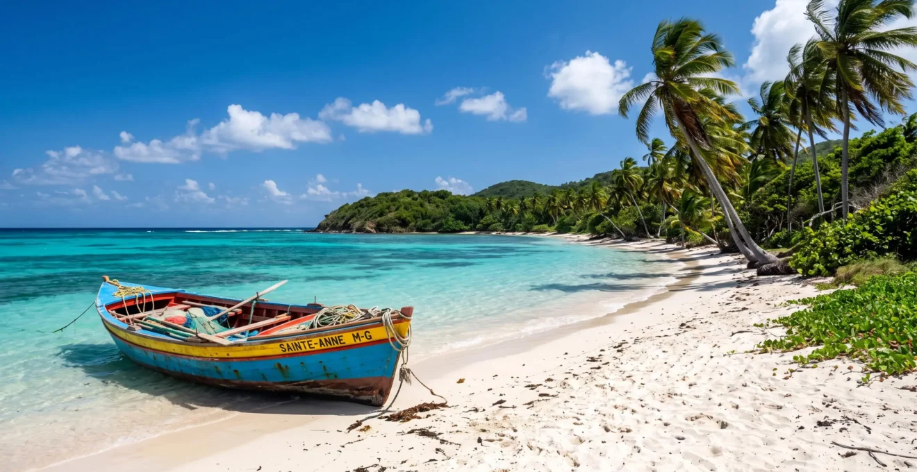 Plage sauvage de Marie-Galante avec bateau de pêcheur traditionnel coloré sur sable blanc, eau turquoise cristalline et cocotiers naturels